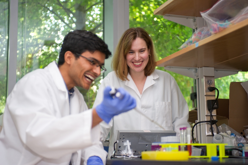 Two students laughing in a research lab.