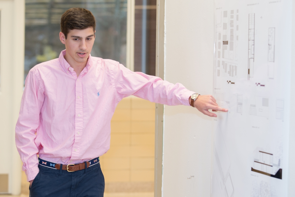 Image a student presenting and referencing his work on the whiteboard.