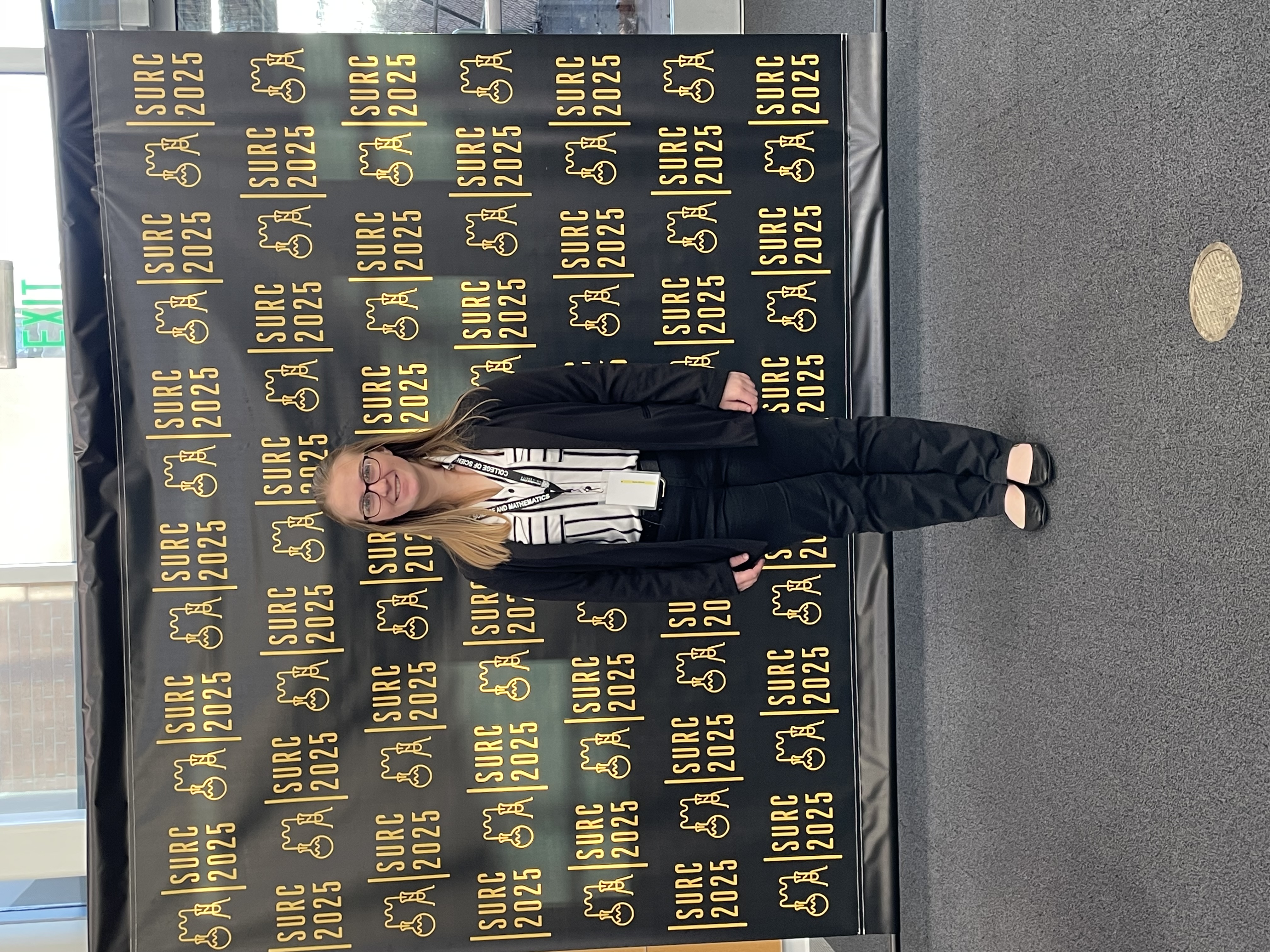 Sara stands in front of a SURC2025 Background