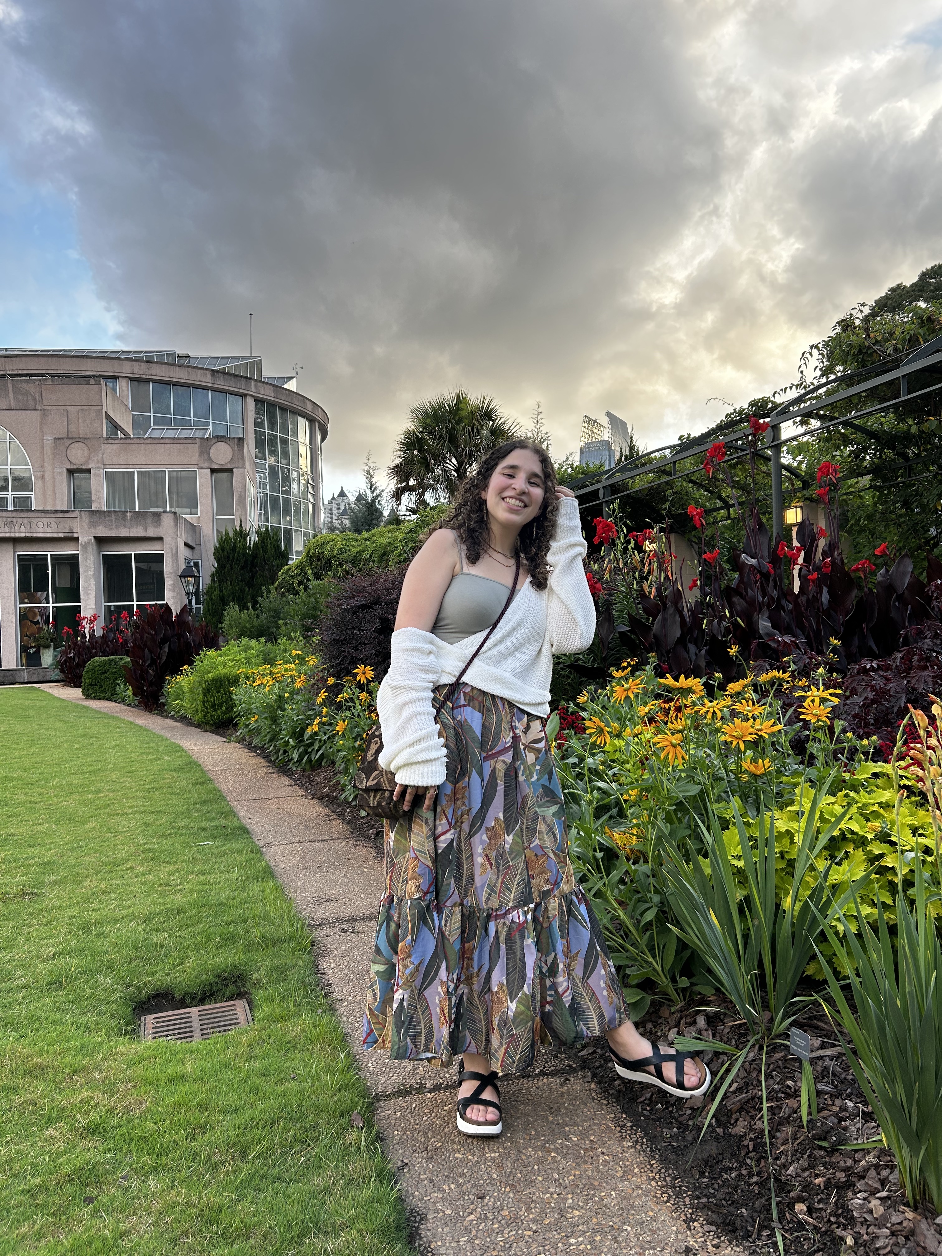 Vicky smiles whiles standing in a garden.