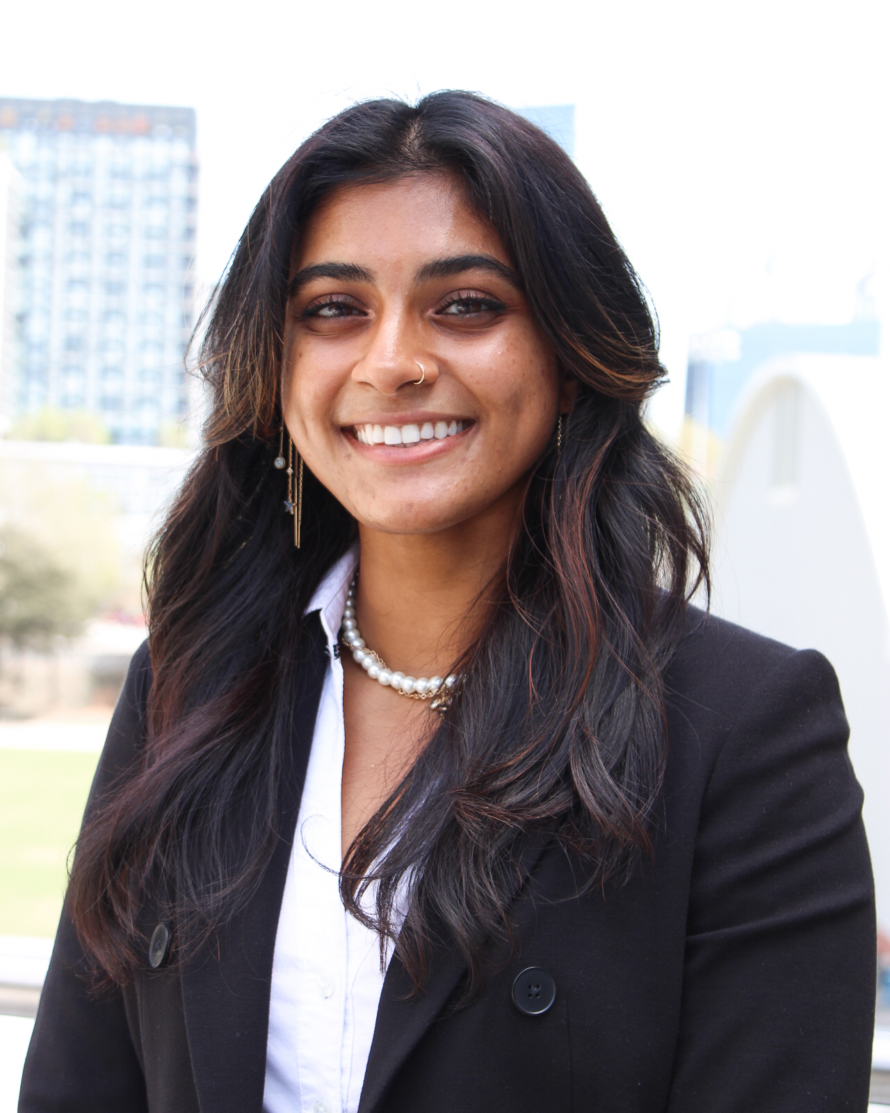 Headshot of Anisha Kanukalanu, a woman with long dark hair in a white shirt and black blazer.