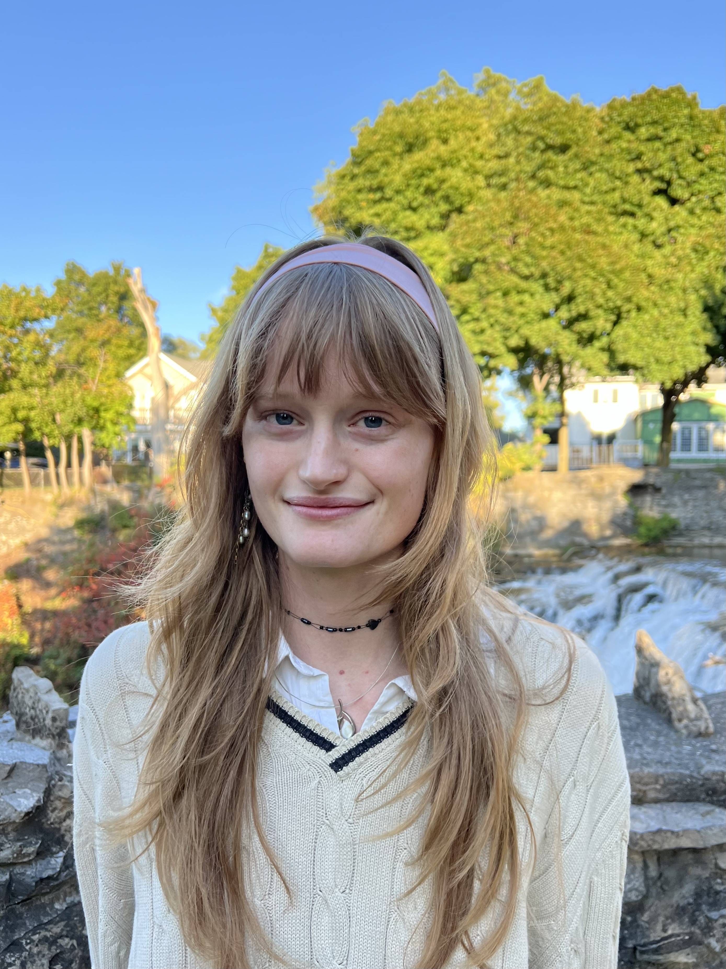 Megan smiles at the camera, standing in a setting with landscape behind her.