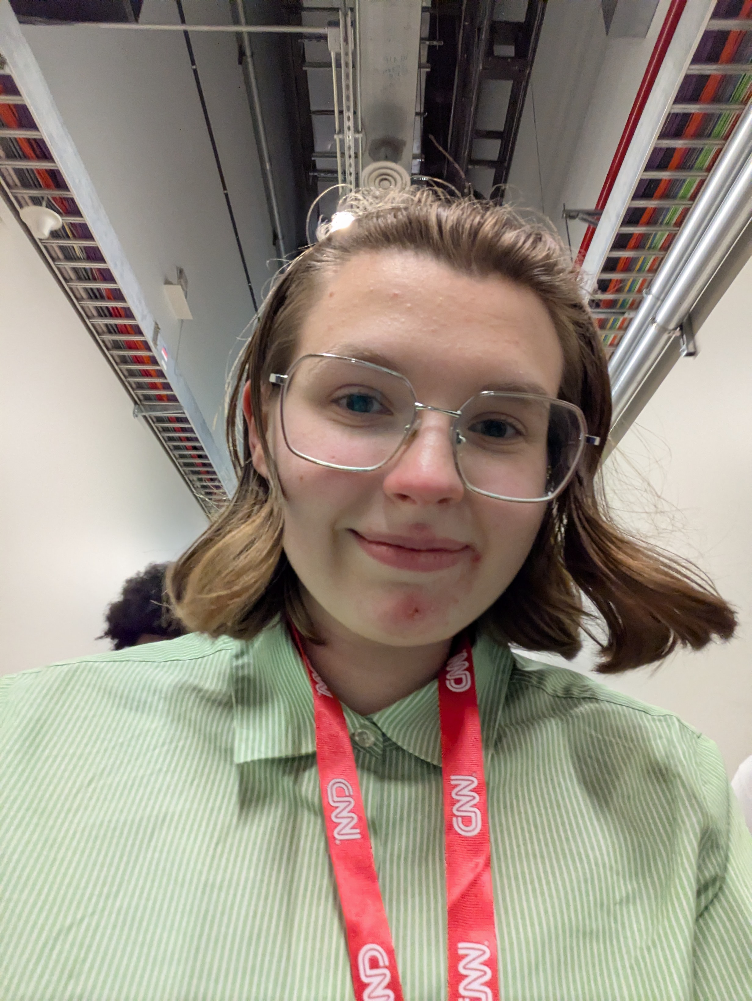 Olivia smiles at the camera, wearing a lanyard that says "CNN."